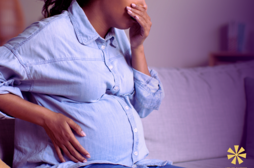 Une femme enceinte met la main devant sa bouche car elle a des nausées.
